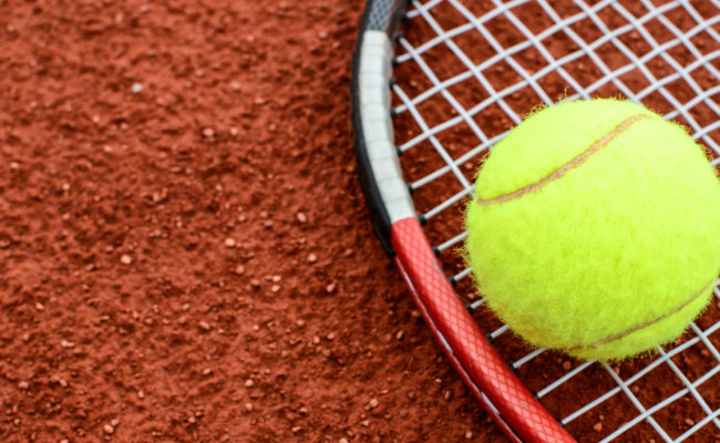 Tennis ball and racquet on clay macro shot